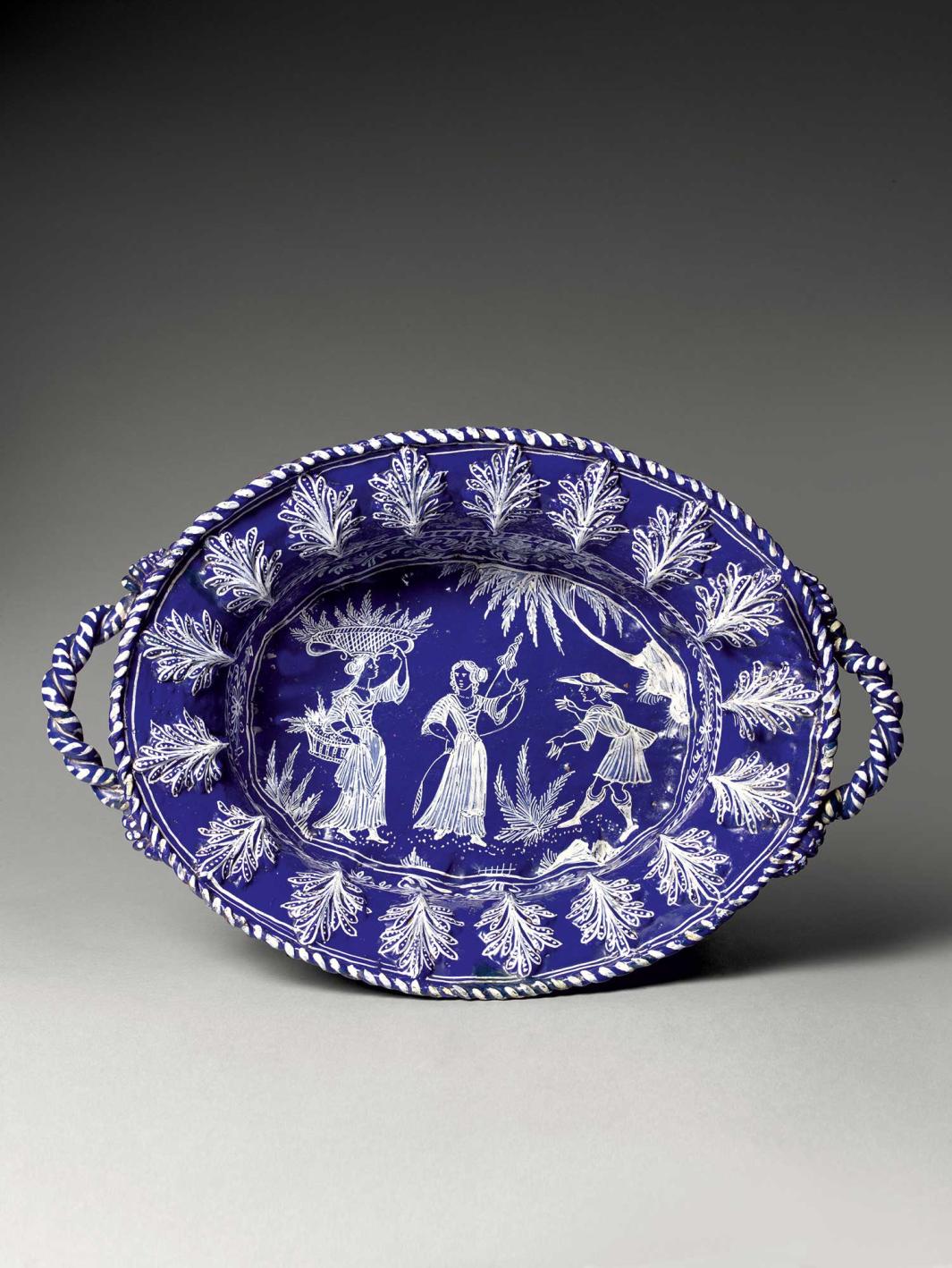 Blue earthenware basin with a three figures at the center and plants around the edge in white