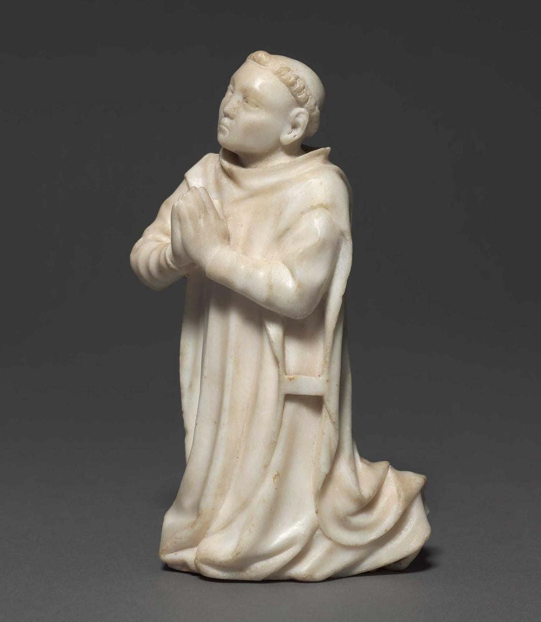 white marble sculpture of kneeling monk