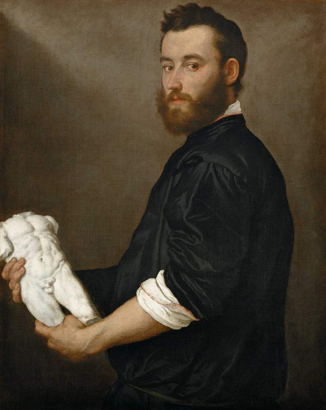 oil painting of bearded young man wearing black garment. In his hands he holds a sculpture of a nude male torso.