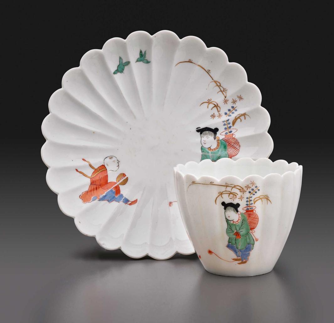 fluted tea cup and saucer with Asian-style figures