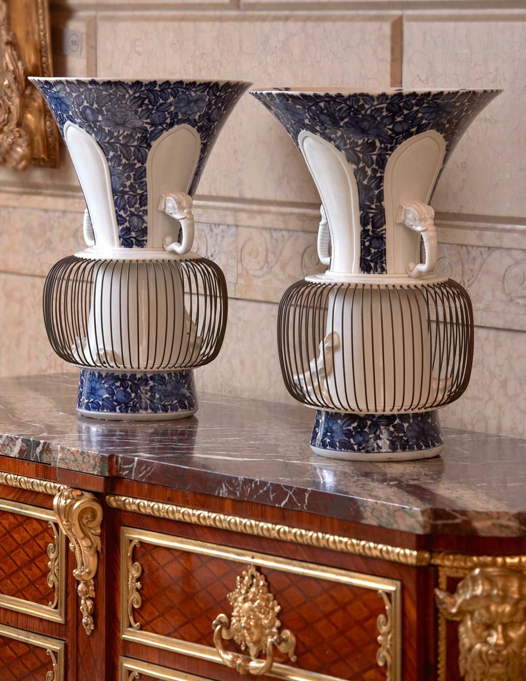 White porcelain vases with blue glaze, a birdcage at the bottom and a handle on each side in the shape of an elephant's head with trunk