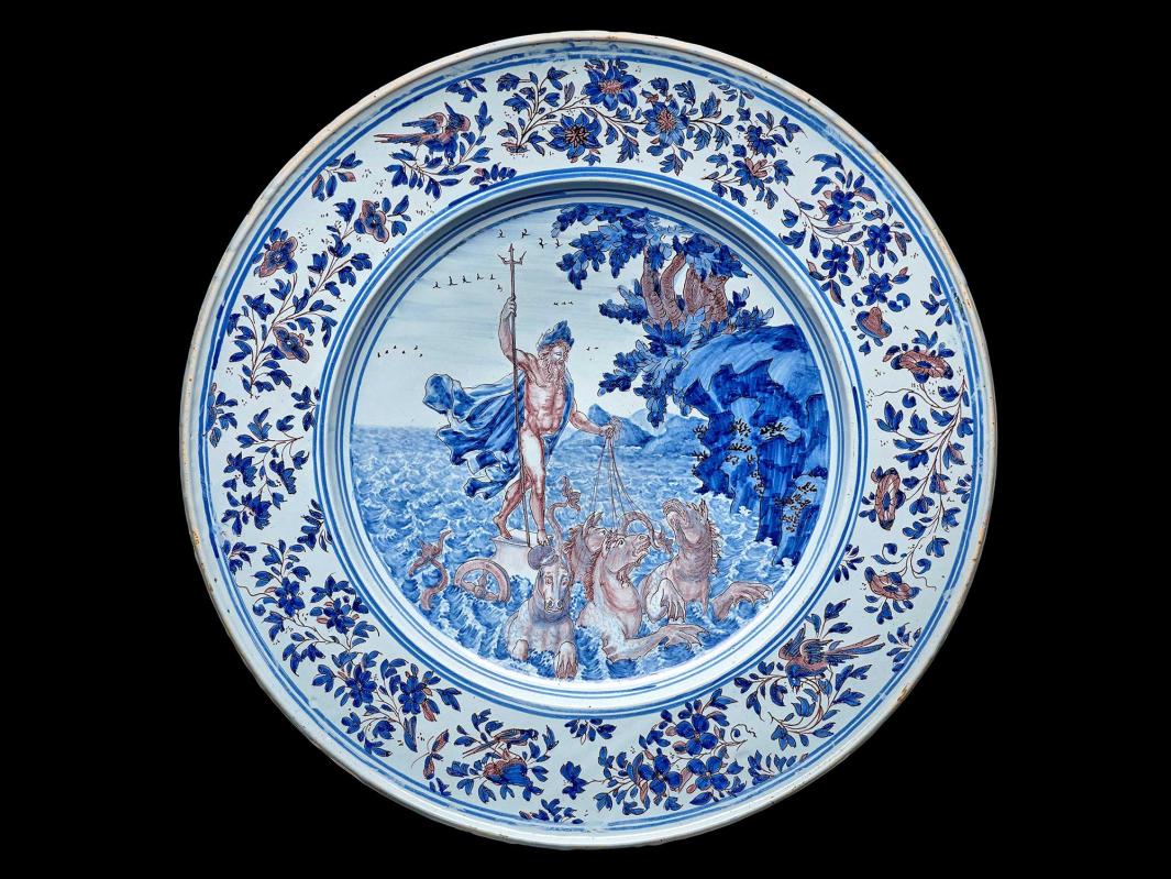 Earthenware plate with a scene of Poseidon riding his chariot in a seascape at the center and a floral design around the edge