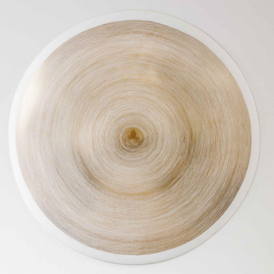 white ceramic disk painted with thin, gold concentric circles and a gold fingerprint at center 