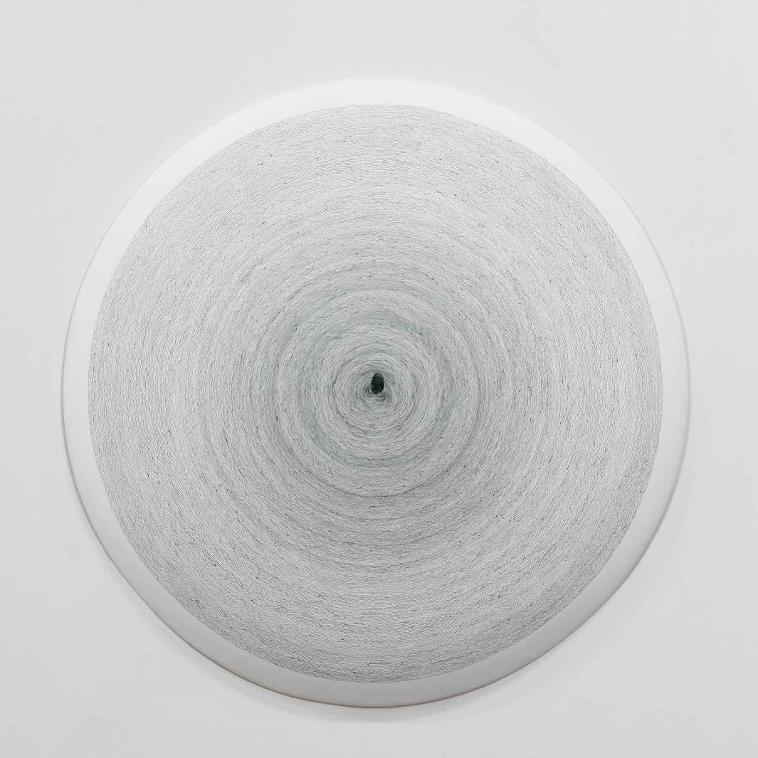 white ceramic disk painted with thin, gray concentric circles and a gray fingerprint at center