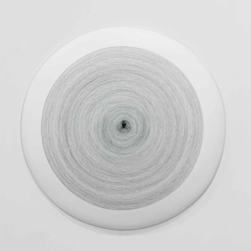 white ceramic disk painted with thin, gray concentric circles and a gray fingerprint at center