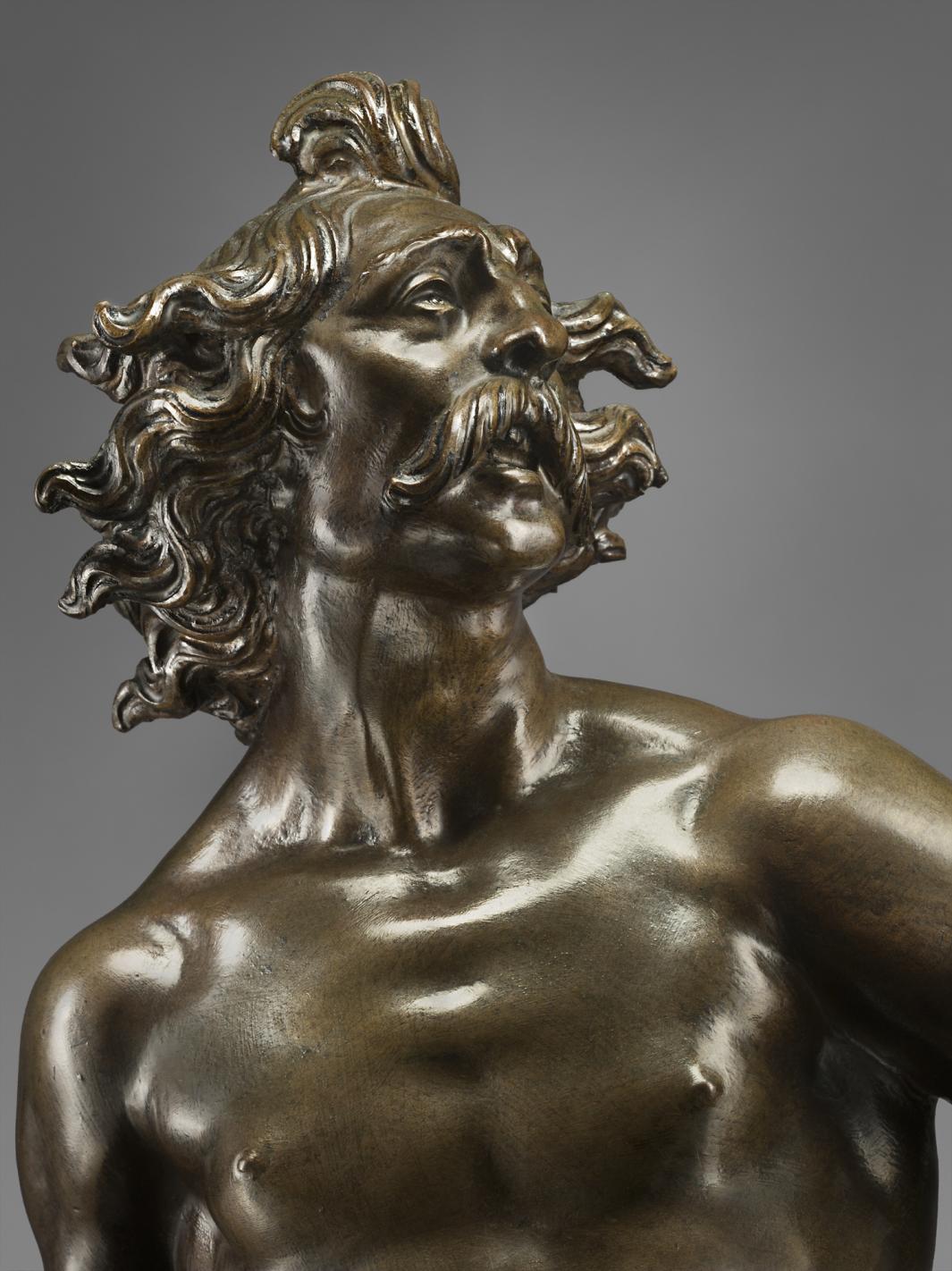 Bronze statue of man striding forward, close up of face.