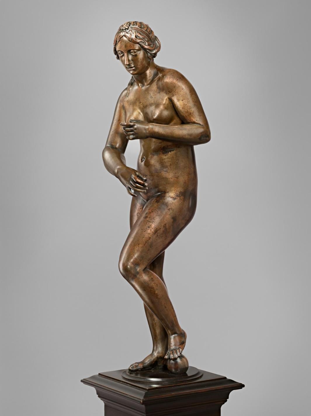Bronze sculpture of standing nude woman.