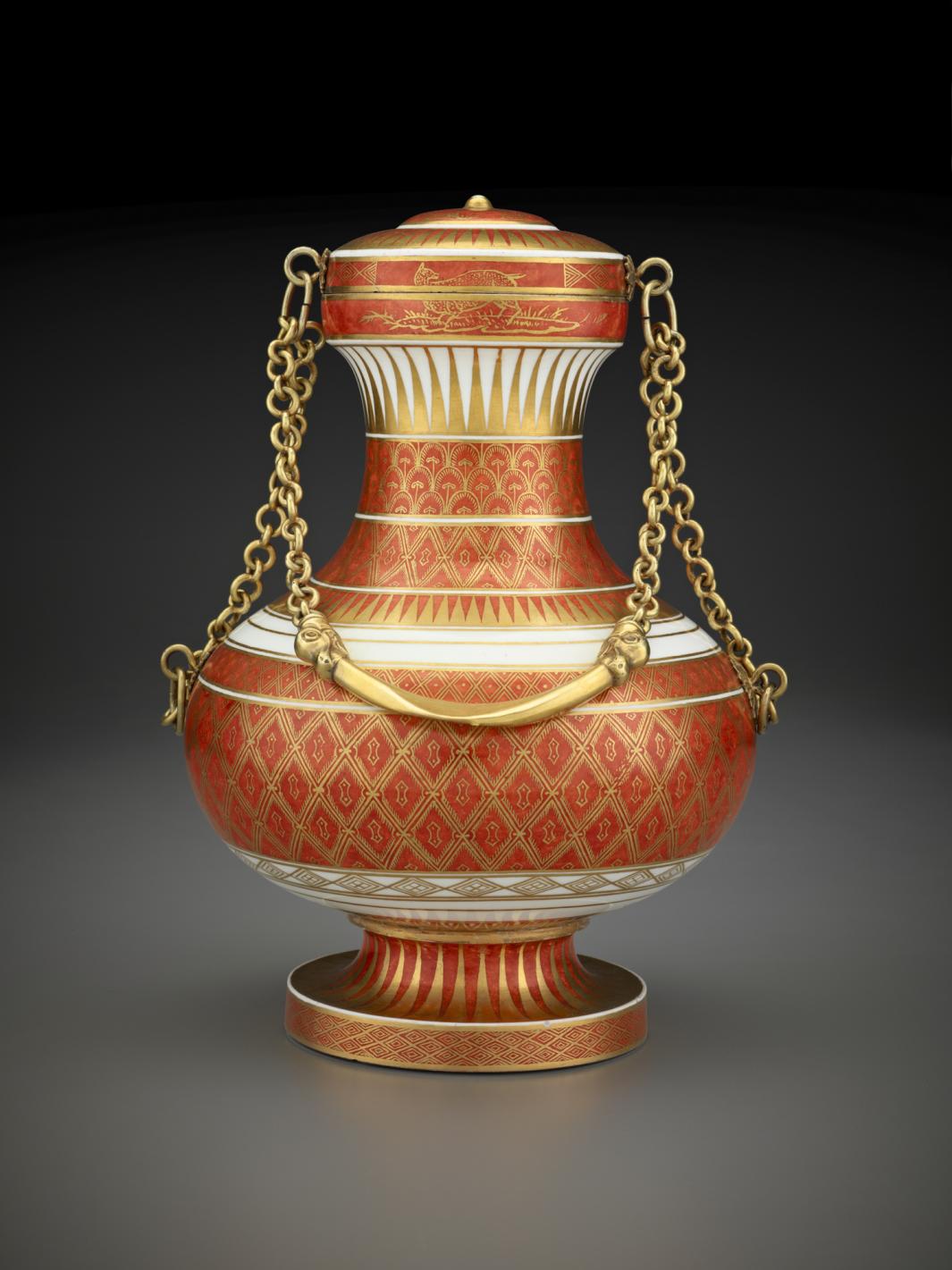 white covered porcelain vase with rust colored diamond pattern and a gold chain