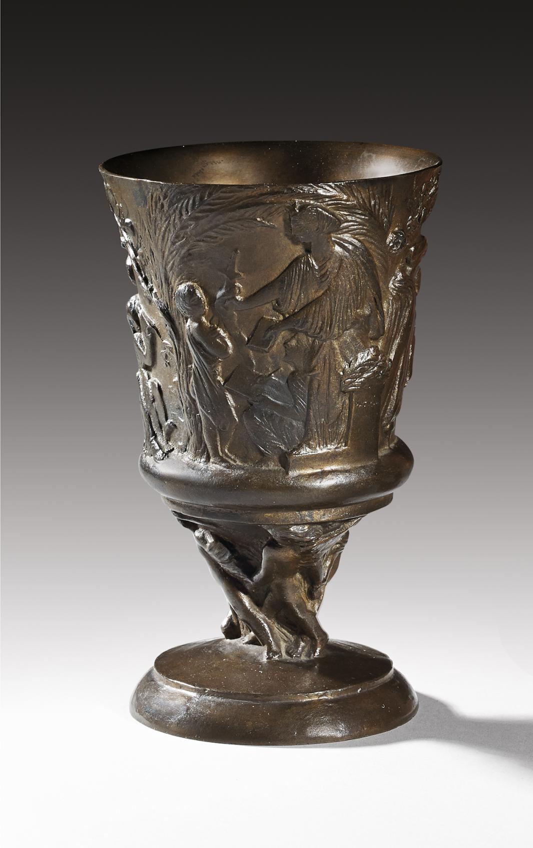 sculpted bronze cup with cast images of palm trees, woman, and child