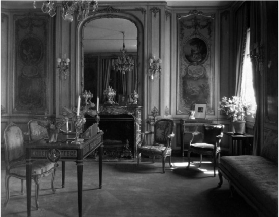 Black-and-white photograph of a lady's boudoir, featuring decorative elements, furniture, and two panels by François Boucher hanging on the back wall