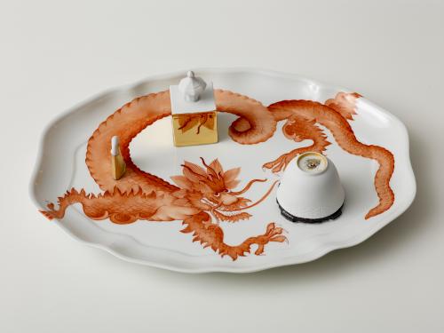 photo of white porcelain dish decorated with large red dragon and cup-like objects