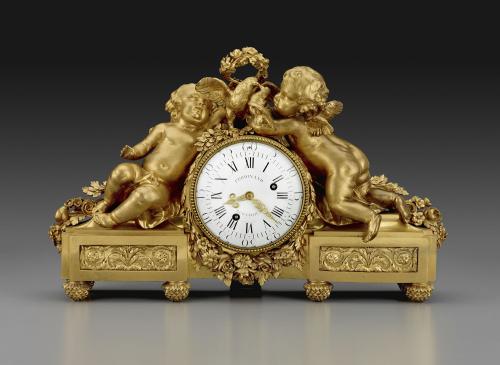 Photograph of gold mantle clock featuring two putti reclining on either side of clock face