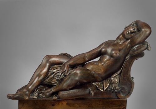Bronze sculpture of sleeping female nude on a bed.