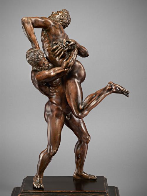 Bronze sculpture of a man wrestling another man.
