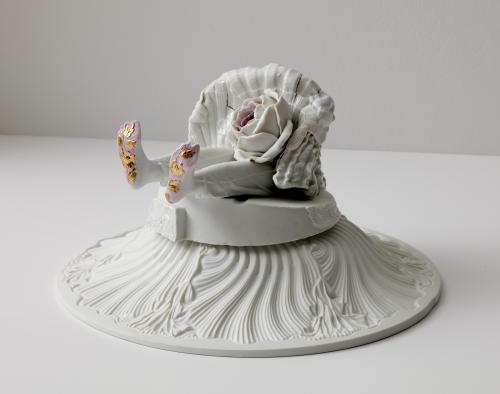 photo of white porcelain figure with outstretched legs connected to rose 