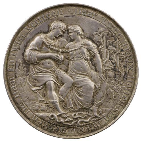 Silver medal depicting a seated couple bathed in sunlight, wearing fanciful classical dress and joined together by a chain from which hangs a heart, trample three serpents underfoot; in the background, a grapevine trained on two posts, and a flowering plant 