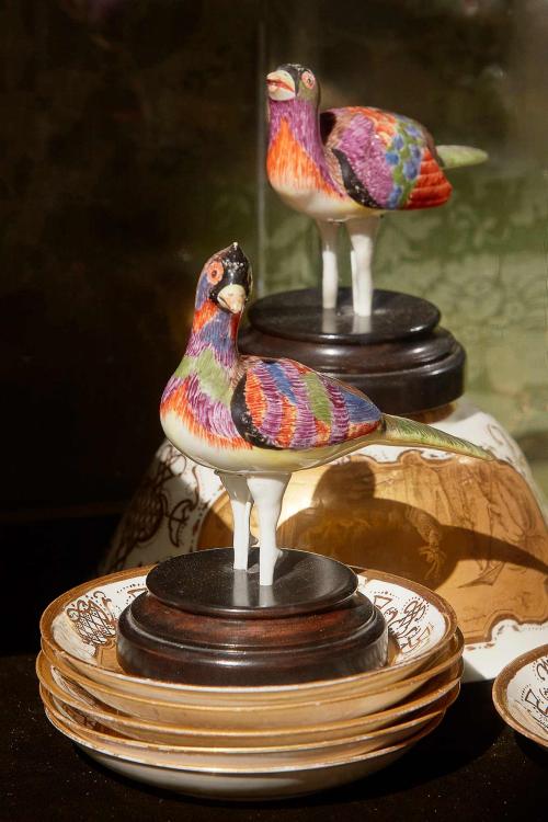 two colorful porcelain birds situated on porcelain dishes