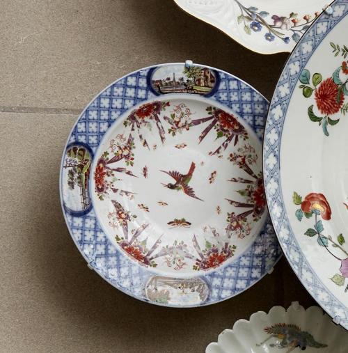 closeup of white porcelain plates, decorated with blue border, landscape scenes, birds and plants 