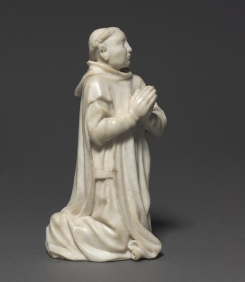 white marble sculpture of kneeling monk