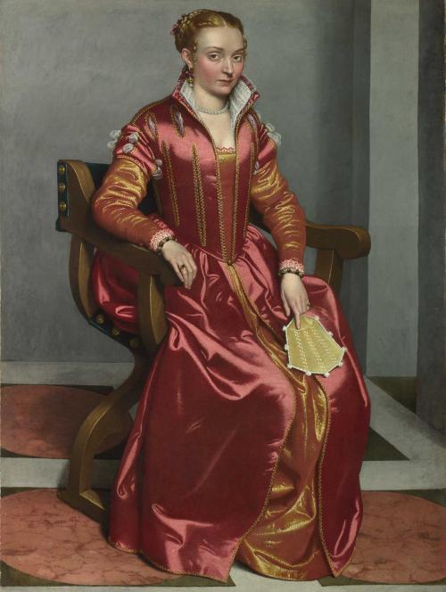 oil painting of a seated young noblewoman dressed in a shining red gown. In her left hand she holds a flat fan. 