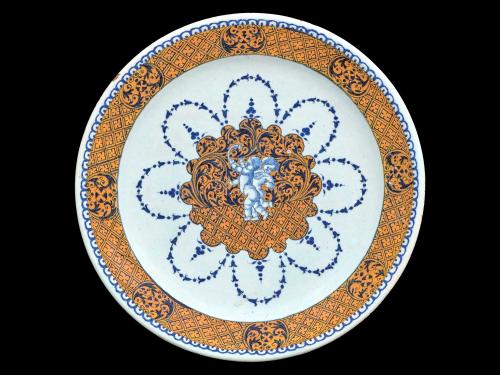 Earthenware plate with two cherubs in the center surrounded by floral designs in blue and orange