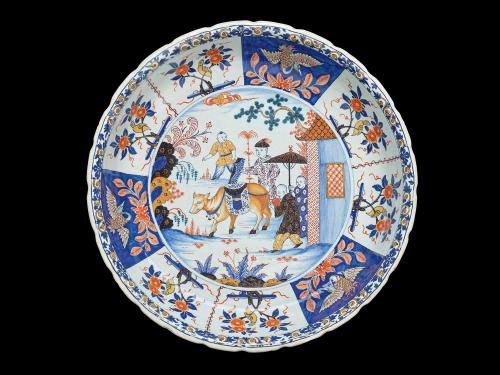 Earthenware dish with a scene of a cow surrounded by four figures in the center and birds and plants on the outside