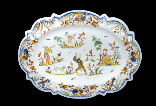 Earthenware platter with four figures in a landscape-like setting with plants, insects and animals.