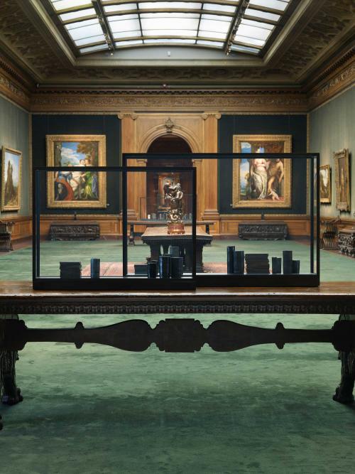 View of the West Gallery looking west with two black vitrines containing black porcelain vessels and steel blocks