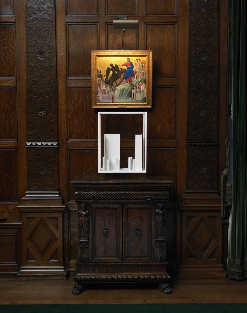 Vitrine containing white porcelain vessels, white steel and gold against a dark wood background