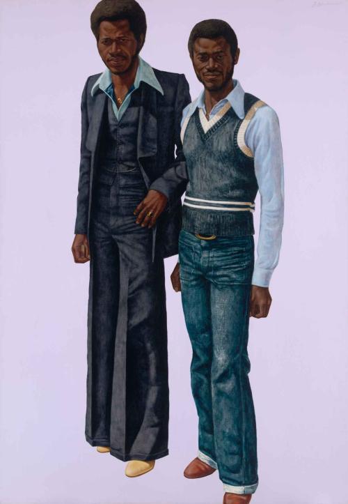 Portrait of two men, one in jeans and a sweater, the other in a suit, against a lavender background.
