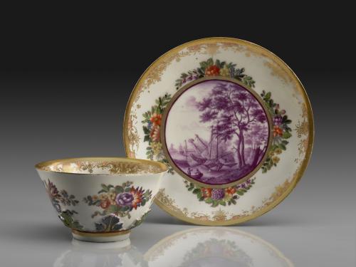 photo of white porcelain saucer and tea bowl decorated with gold, flowers, and purple landscape