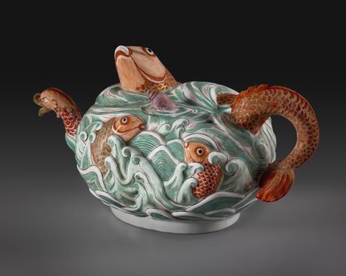 photo of porcelain teapot textured with green waves and orange fish