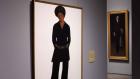 video still of full length portrait of woman dressed in black in gallery