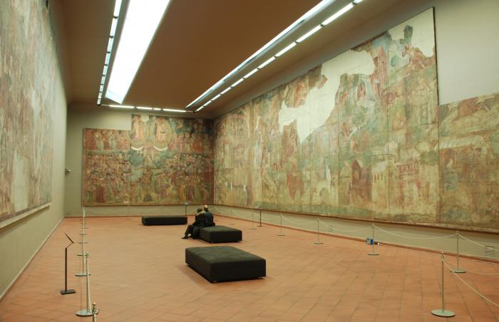 Gallery with large color frescoes spanning the entire wall, with some patches missing
