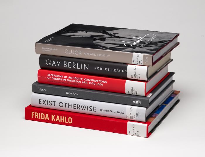 Stack of six books on LGBTQ+ art and history, with spines showing against a gray background