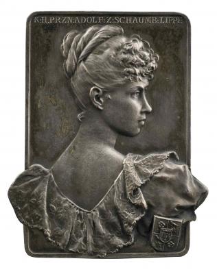 Copper medal of a woman overlooking her right shoulder wearing a dress with a low back and lace collar