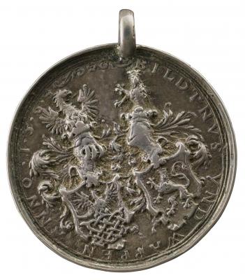 Silver medal depicting two heraldic shields surmounted by helmets