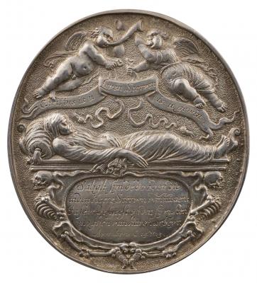 Silver medal depicting two flying genii, one clothed and one nude, sounding horns, each holding a ribbon ending in a tassel and a banner; below, a corpse wrapped in a shroud and resting, head supported by a bolster, on a tomb; beneath, a cartouche flanked by two contorted skeletons