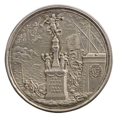 Silver medal of a statue of a trumpeting angel standing on a plinth, with four figures standing around the base, with cannons behind the plinth, and a ship and island in the background. Four winged, naked children fly in the upper right corner of the background