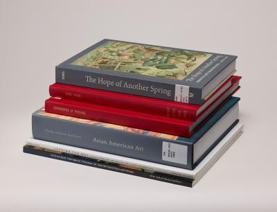 Stack of six books on Asian and Pacific Islander American art history, against a gray background