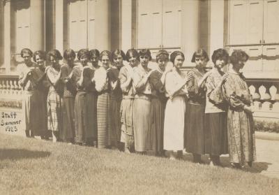 Fifteen women standing in a row in front of a building