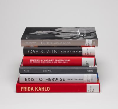 Stack of six books on LGBTQ+ art history with spines showing against a gray background