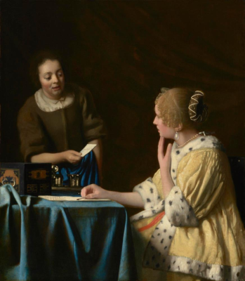 Woman seated at a table, looking back at a woman handing her a letter