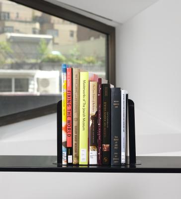 Stack of nine books on a black cart in front of a window