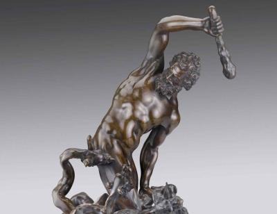 sculpture of nude man with club on top of monster