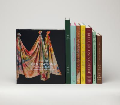 Stack of books next to a book cover featuring a colorfully painted draped canvas