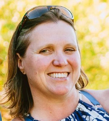 A woman smiling with sunglasses on her head