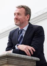 A man leaning on a stone railing of a staircase