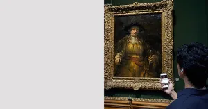 man standing in front of a painting in Frick gallery using a mobile guide