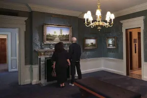 two people standing in Frick gallery with paintings and chandelier